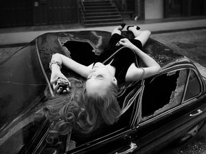 Map of the Heart Black heart perfume V.2 lookbook imagery - woman lying on car with black heart bottle in hand