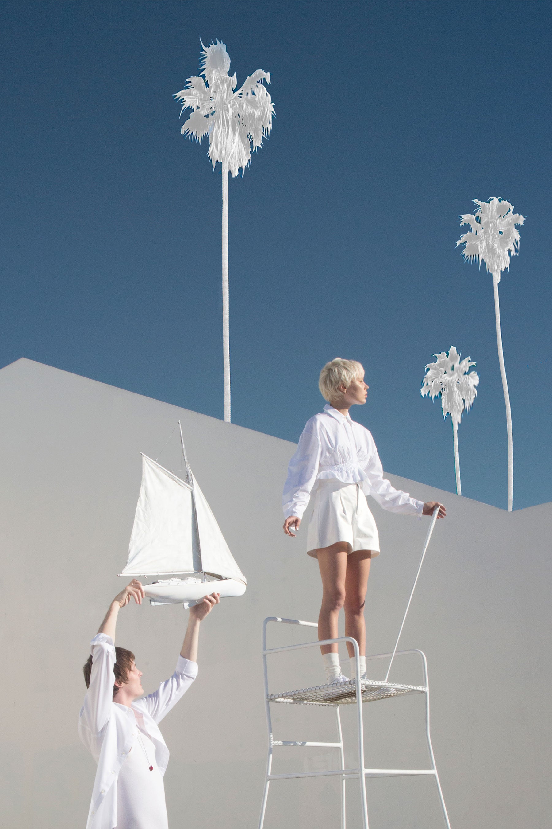 Map of the Heart White v.7 eau de parfum lookbook imagery - Woman stand son high chair looking up to palm trees in sky